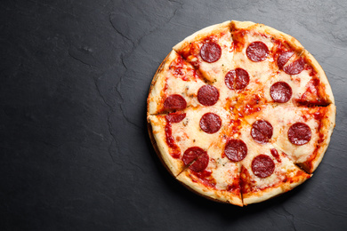 Photo of Hot delicious pepperoni pizza on dark table, top view. Space for text