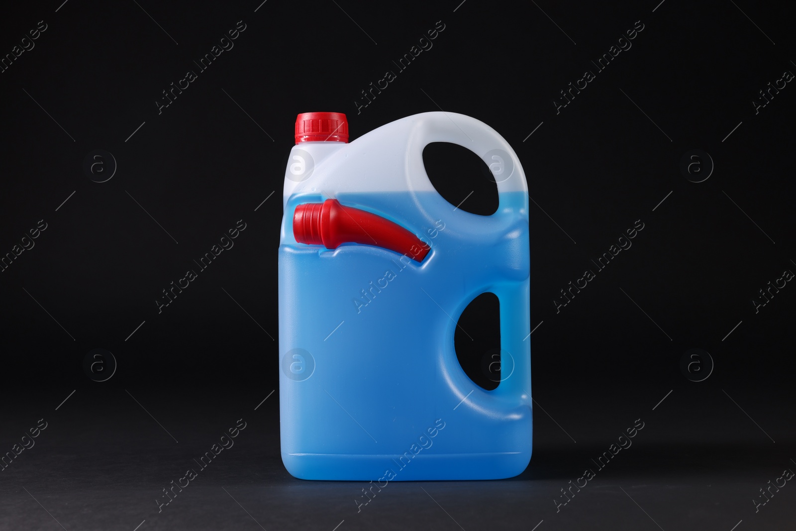 Photo of Plastic canister with blue liquid on black background