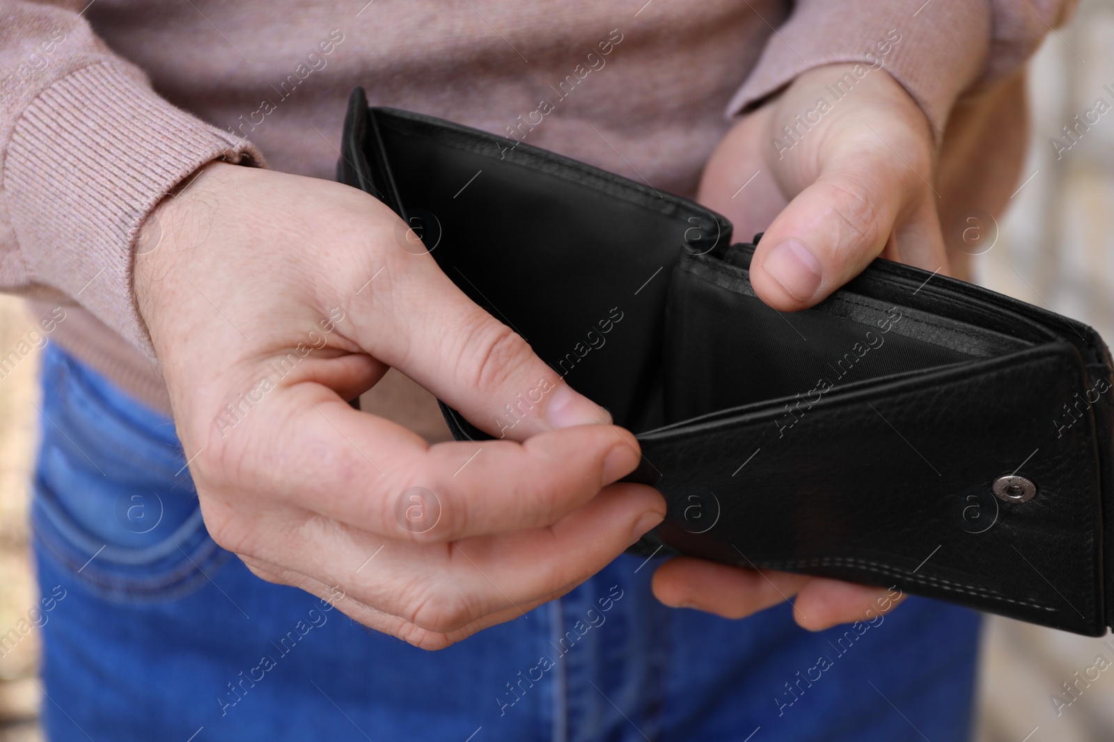 Photo of Poor man holding empty wallet outdoors, closeup