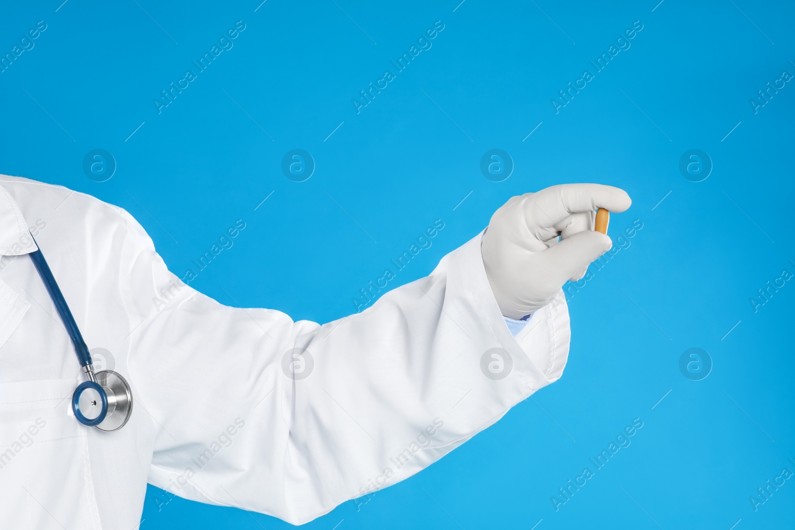 Photo of Doctor holding suppository for hemorrhoid treatment on blue background, closeup