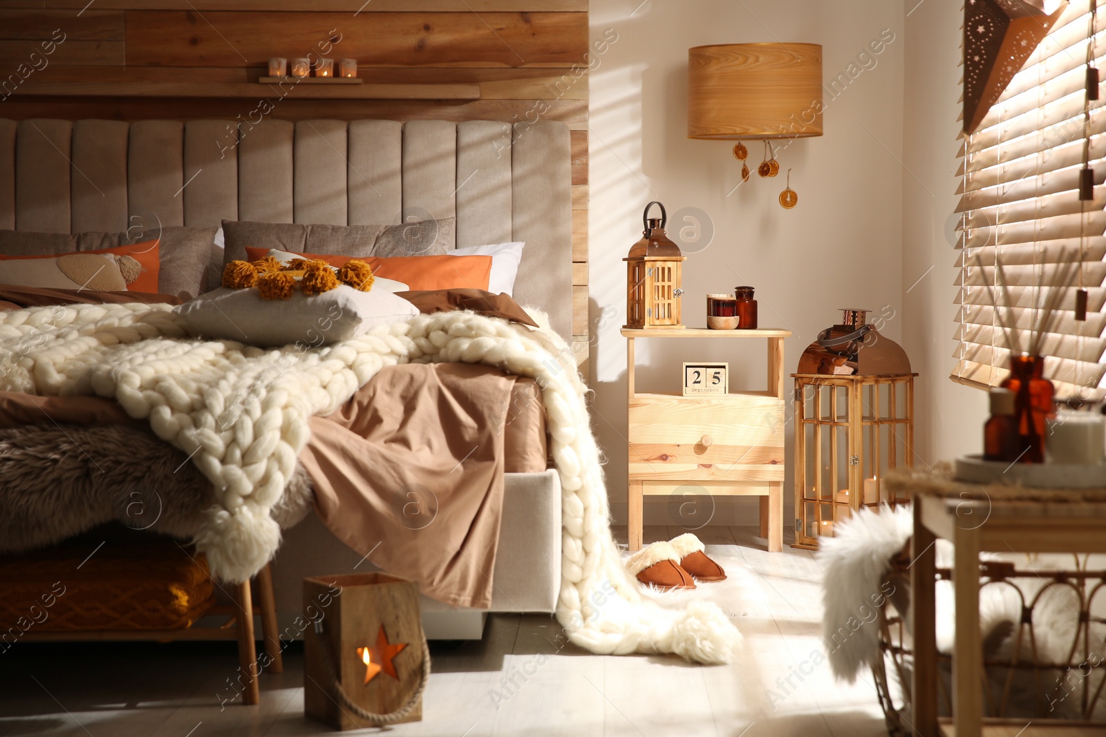 Photo of Cozy bedroom interior with knitted blanket and cushions