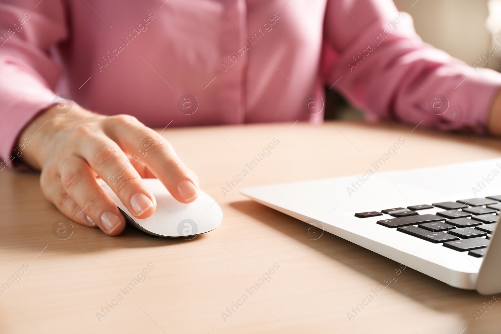 Photo of Woman using computer mouse with laptop at table, closeup