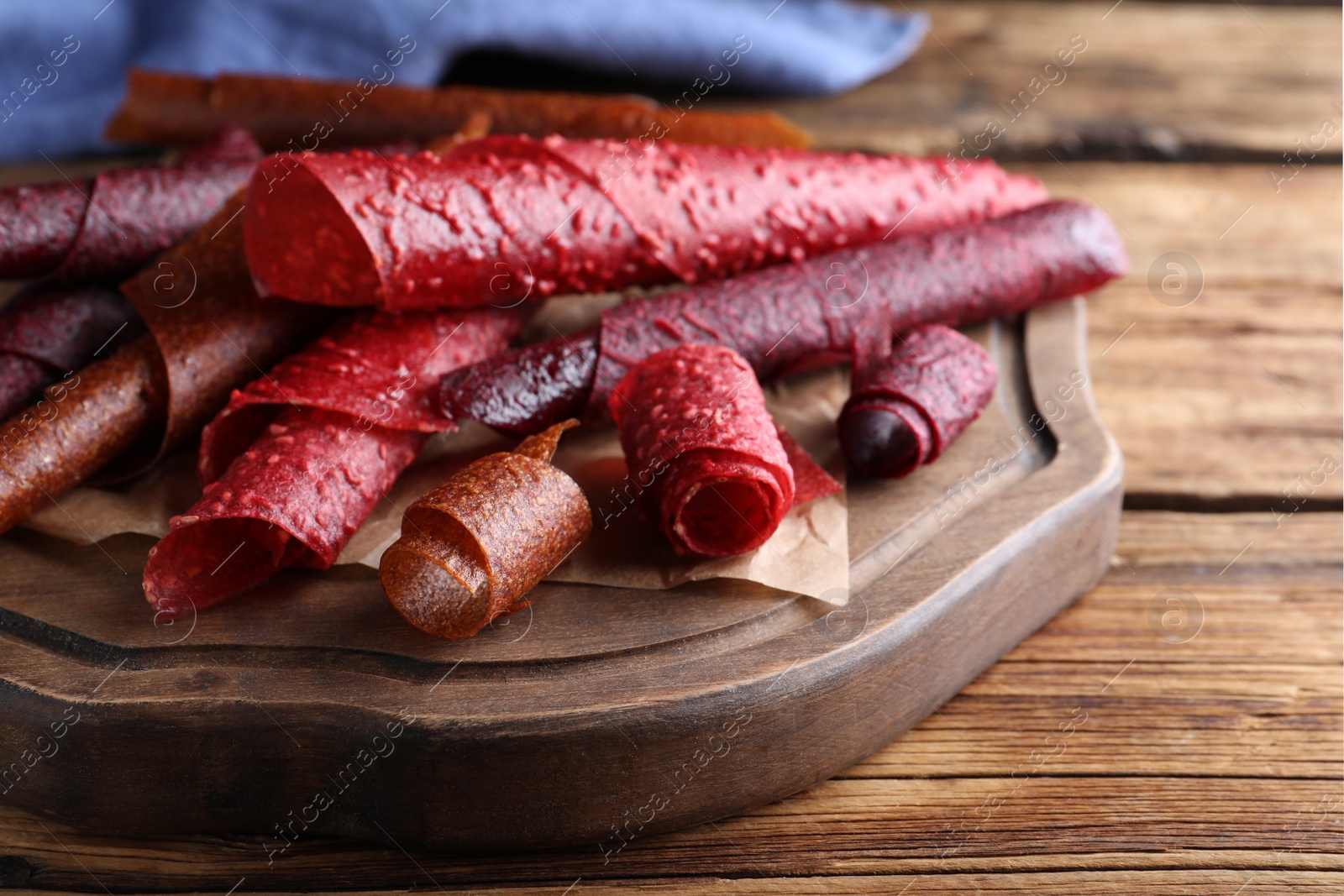 Photo of Delicious fruit leather rolls on wooden table, closeup