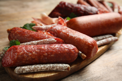 Different types of sausages served on wooden table, closeup