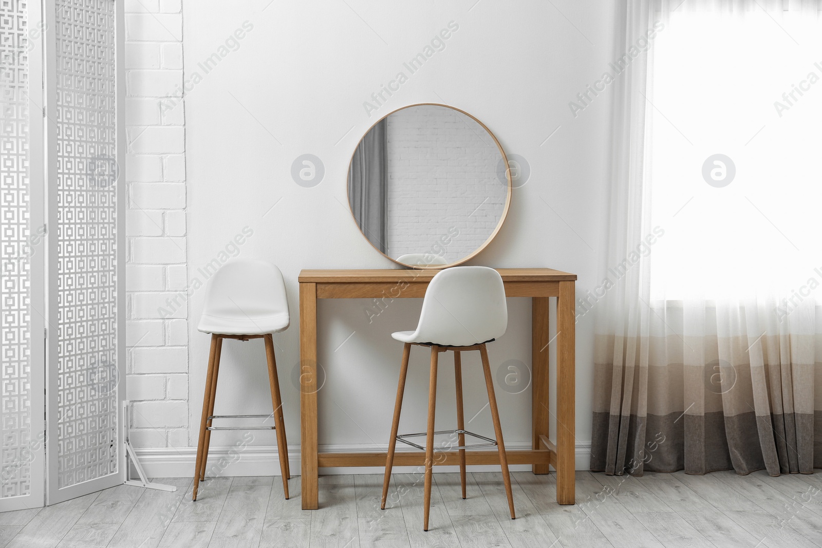 Photo of Makeup room interior with wooden table and mirror near white wall