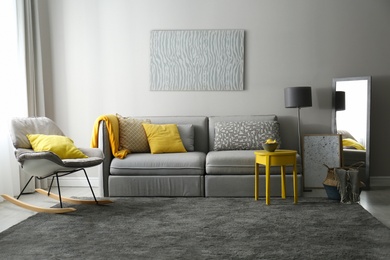 Stylish living room with sofa. Interior design in grey and yellow colors