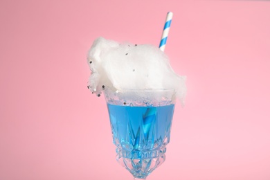 Photo of Cocktail with cotton candy in glass on pink background, closeup view