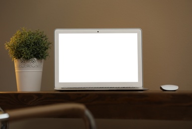 Photo of Laptop with blank screen on table indoors. Space for text