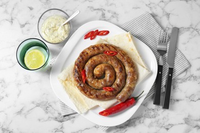 Tasty homemade sausage with chili pepper and lavash served on white marble table, flat lay