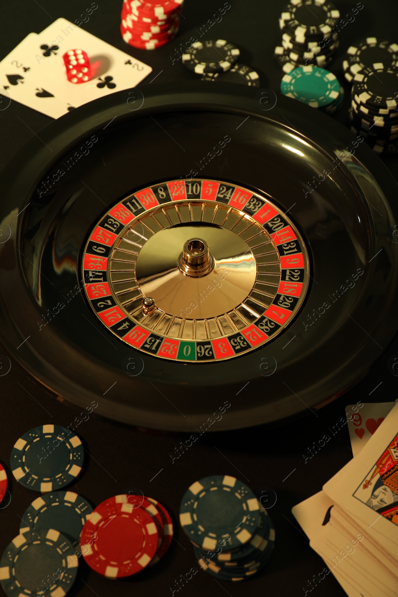 Photo of Roulette wheel, playing cards and chips on table, flat lay. Casino game
