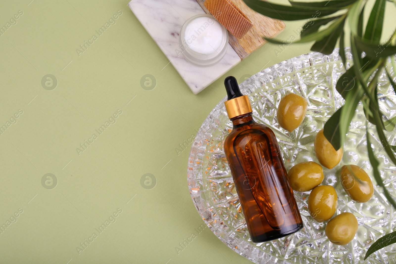 Photo of Cosmetic products, olives and leaves on green background, flat lay. Space for text