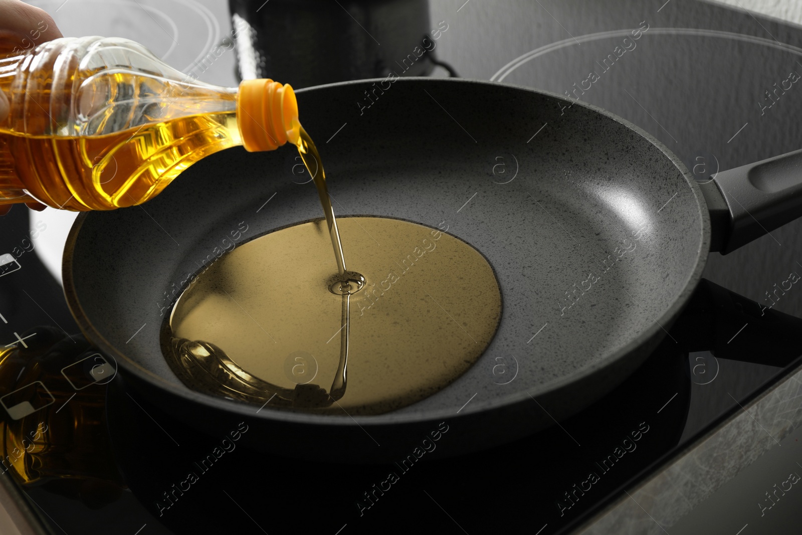 Photo of Woman pouring cooking oil from bottle into frying pan, closeup