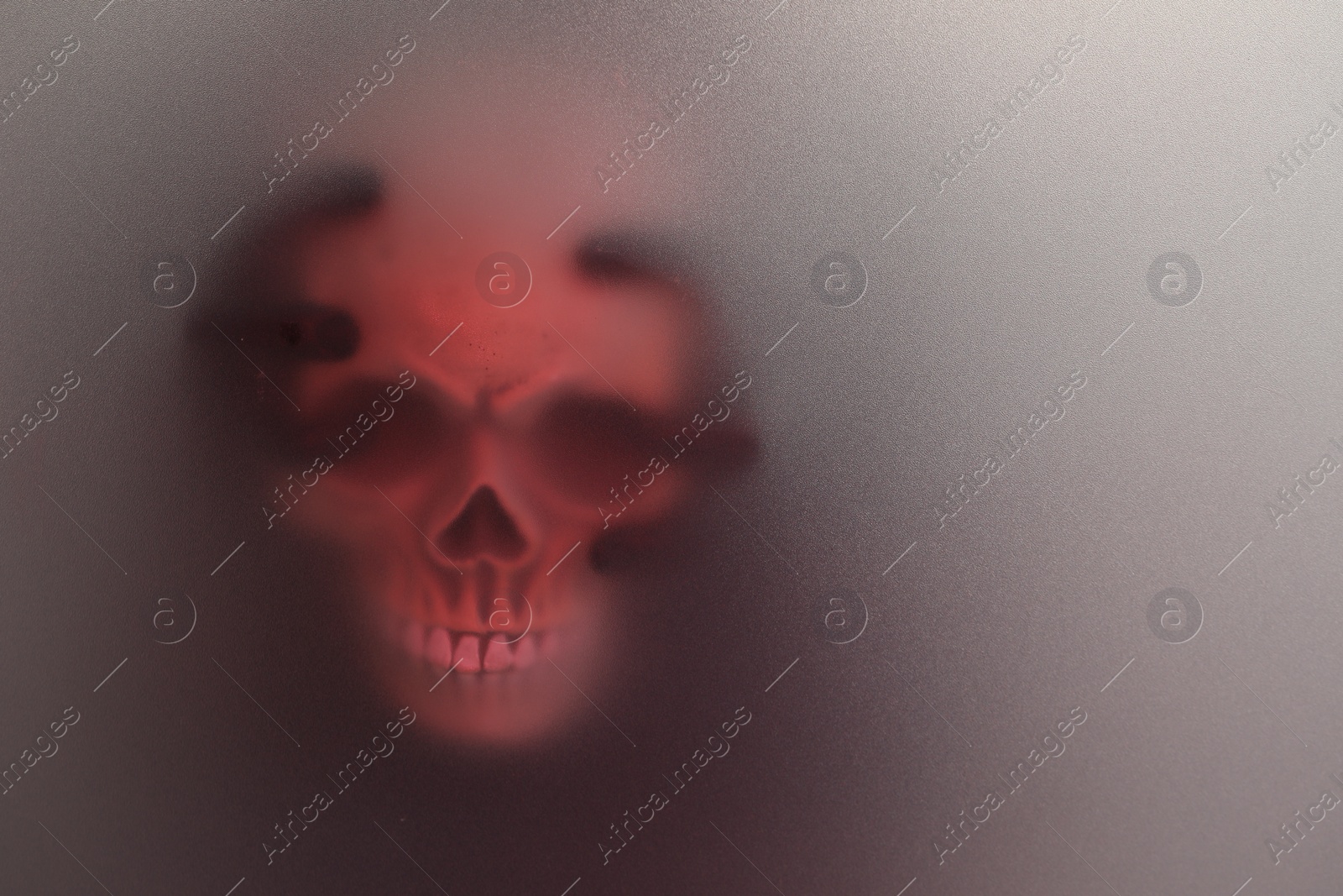 Photo of Silhouette of creepy ghost with skull behind cloth, space for text. Color toned