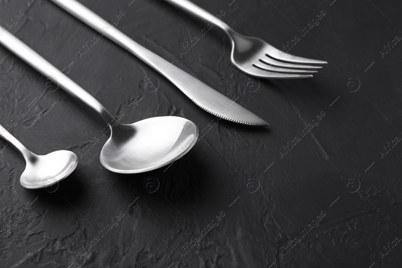 Photo of Beautiful cutlery set on black table, closeup