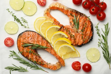 Photo of Tasty grilled salmon steaks and ingredients on white table, flat lay