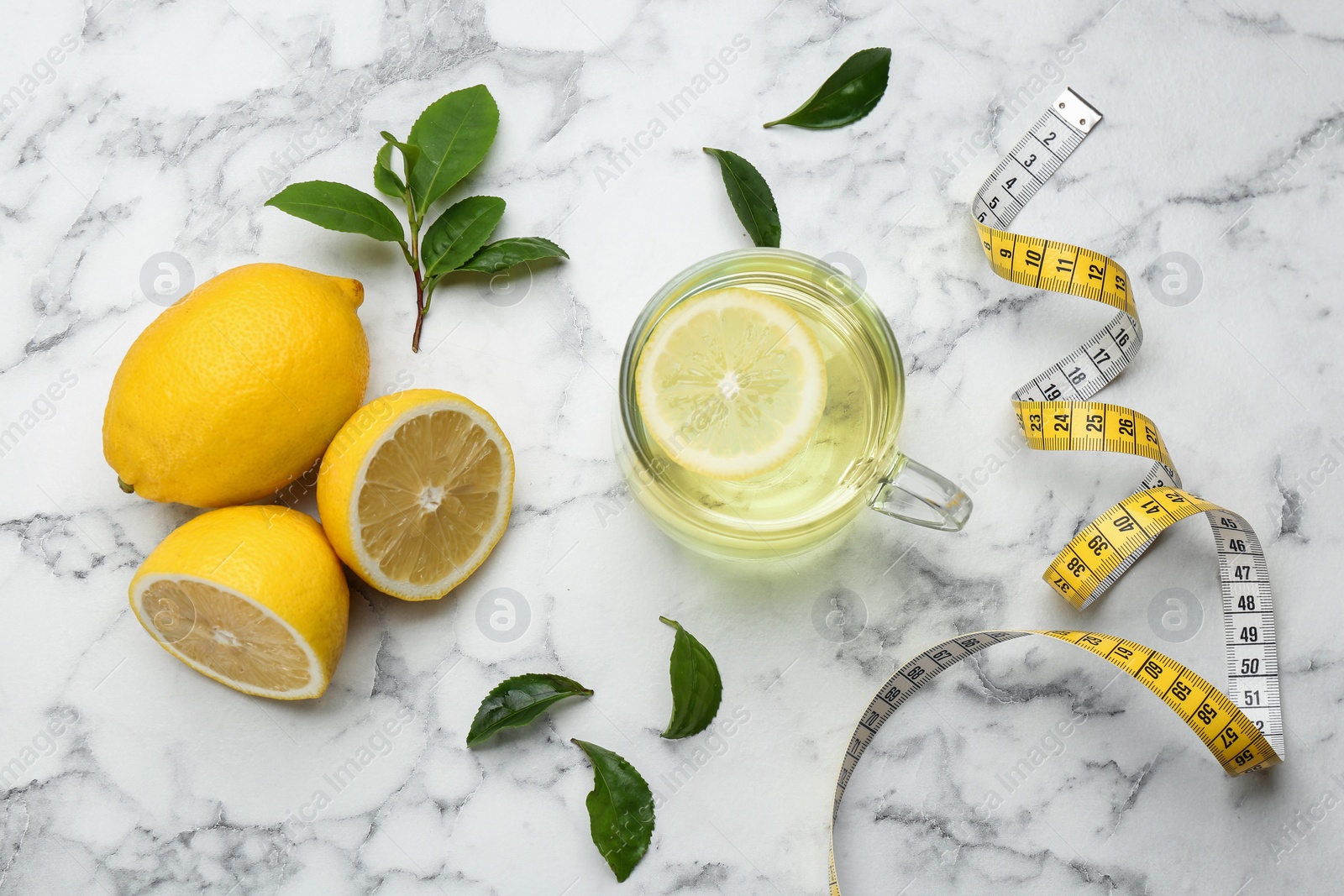 Photo of Flat lay composition with glass cup of diet herbal tea on white marble background