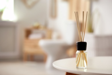 Aromatic reed air freshener on table against blurred background