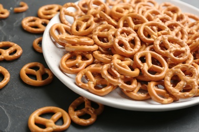 Photo of Delicious pretzel crackers on black table, closeup