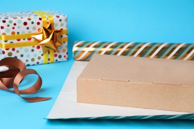 Photo of Roll of wrapping paper, box, ribbon and gift on light blue background