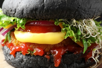 Photo of Tasty black vegetarian burger with sprouts, closeup
