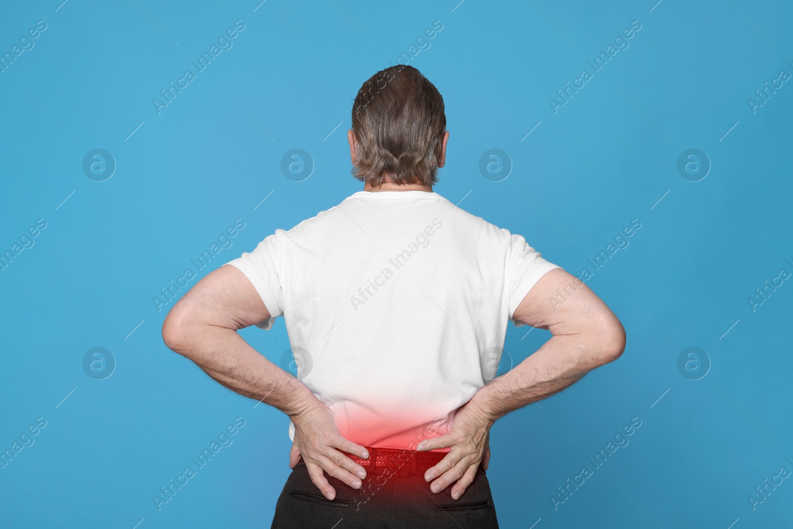 Image of Senior man suffering from pain in lower back on light blue background