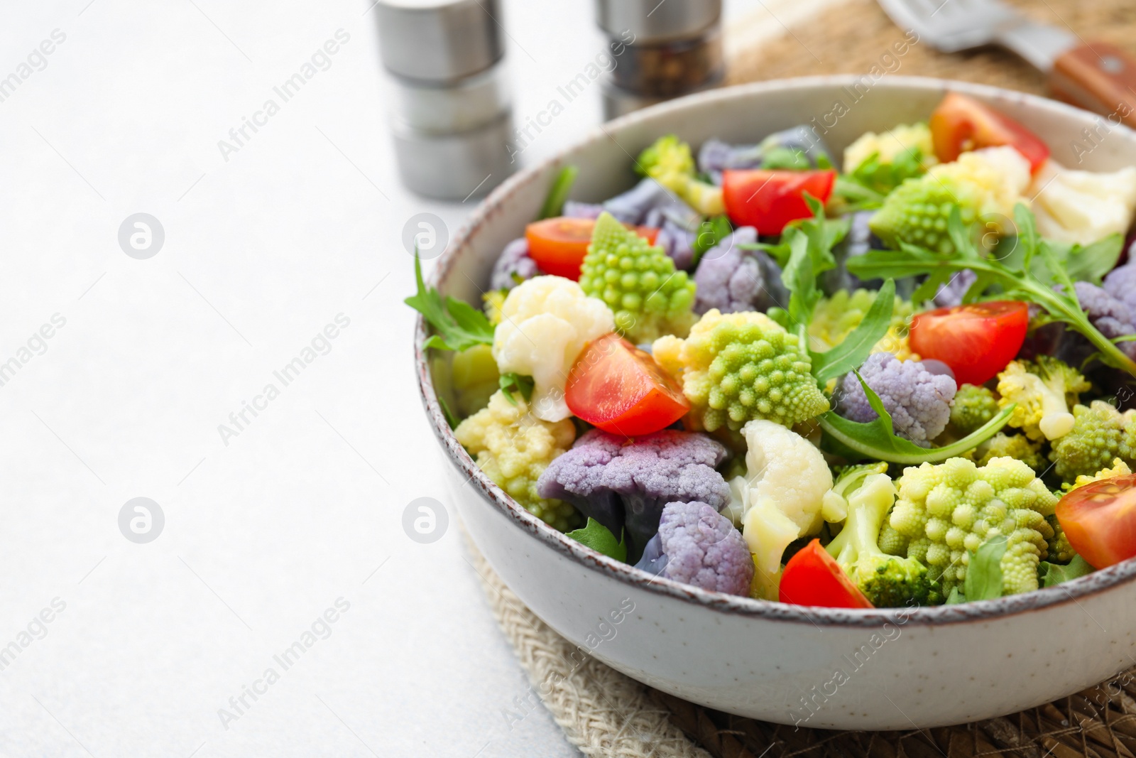 Photo of Delicious salad with cauliflower and tomato served on white table, closeup. Space for text