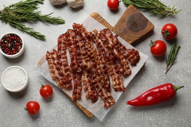 Photo of Slices of tasty fried bacon, tomatoes and different spices on light grey table, top view