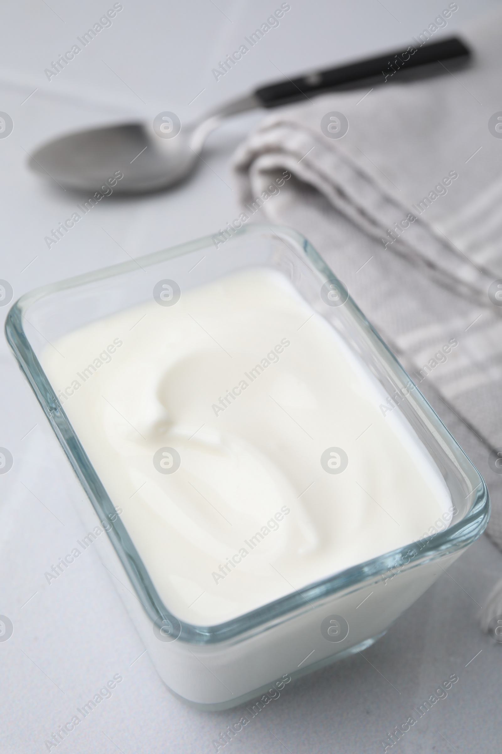 Photo of Delicious natural yogurt in glass bowl on white table, closeup