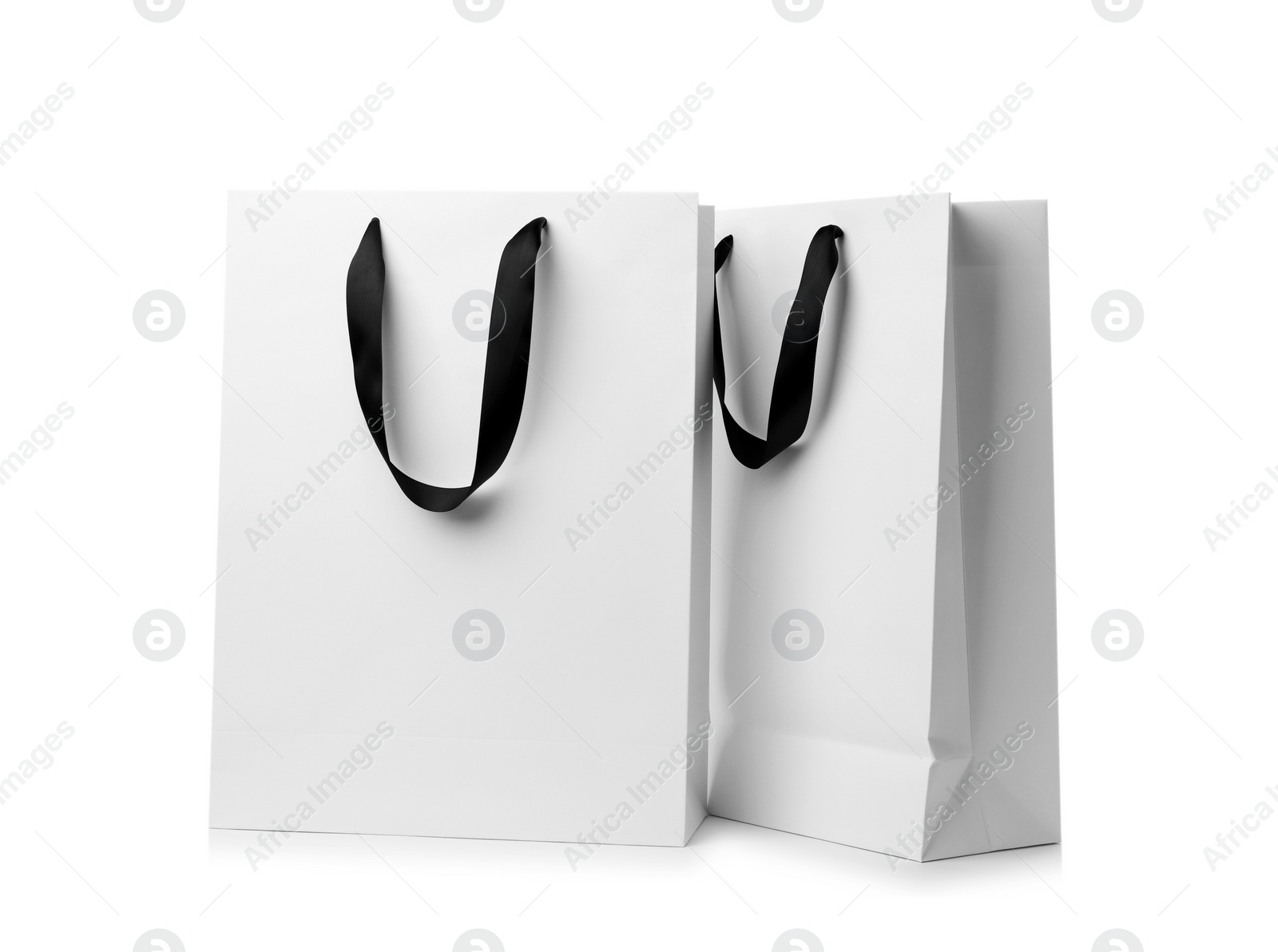 Photo of Paper shopping bags with ribbon handles on white background. Mockup for design