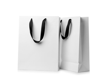 Paper shopping bags with ribbon handles on white background. Mockup for design