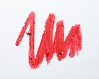 Photo of Red lipstick smear on white background, top view