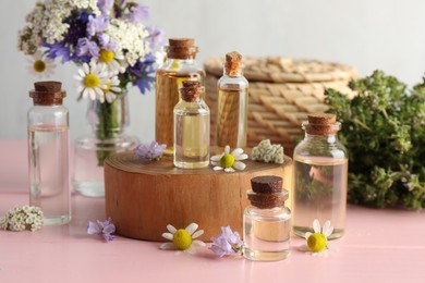 Photo of Aromatherapy. Different essential oils and flowers on pink wooden table