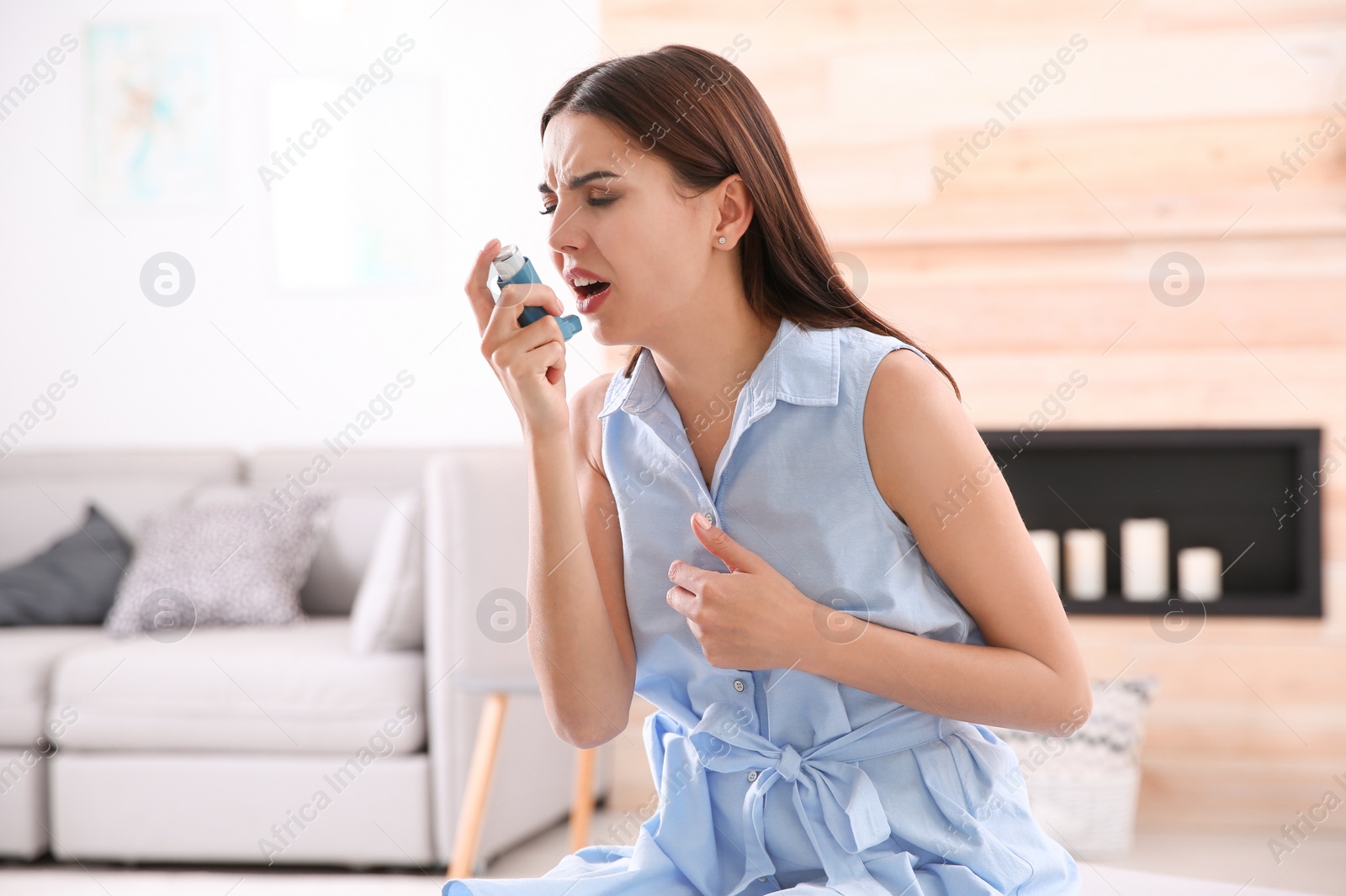 Photo of Young woman with asthma inhaler in light room