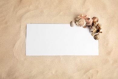 Photo of Flat lay composition with sea shells and blank card on sand, space for text