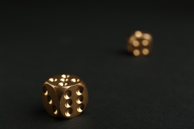 Photo of Gold dices on black background, space for text