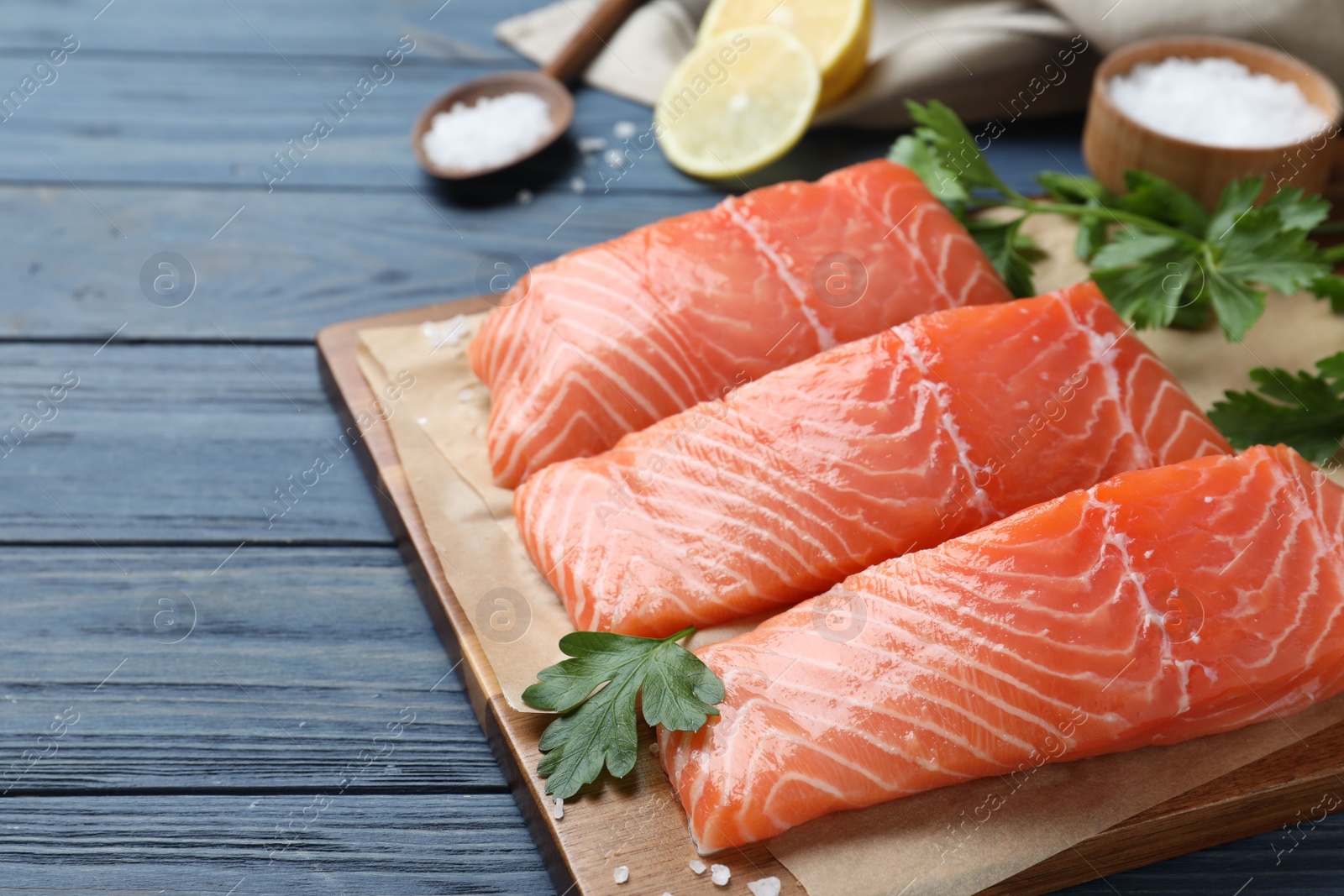 Photo of Fresh raw salmon with parsley on blue wooden table. Fish delicacy