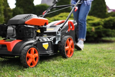 Photo of Woman cutting green grass with lawn mower in garden, selective focus