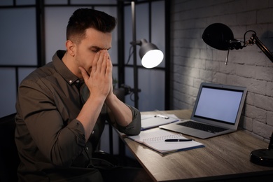 Photo of Overworked man with headache in office