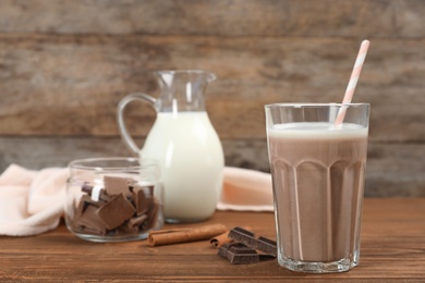 Photo of Glass of chocolate milk on wooden background. Space for text