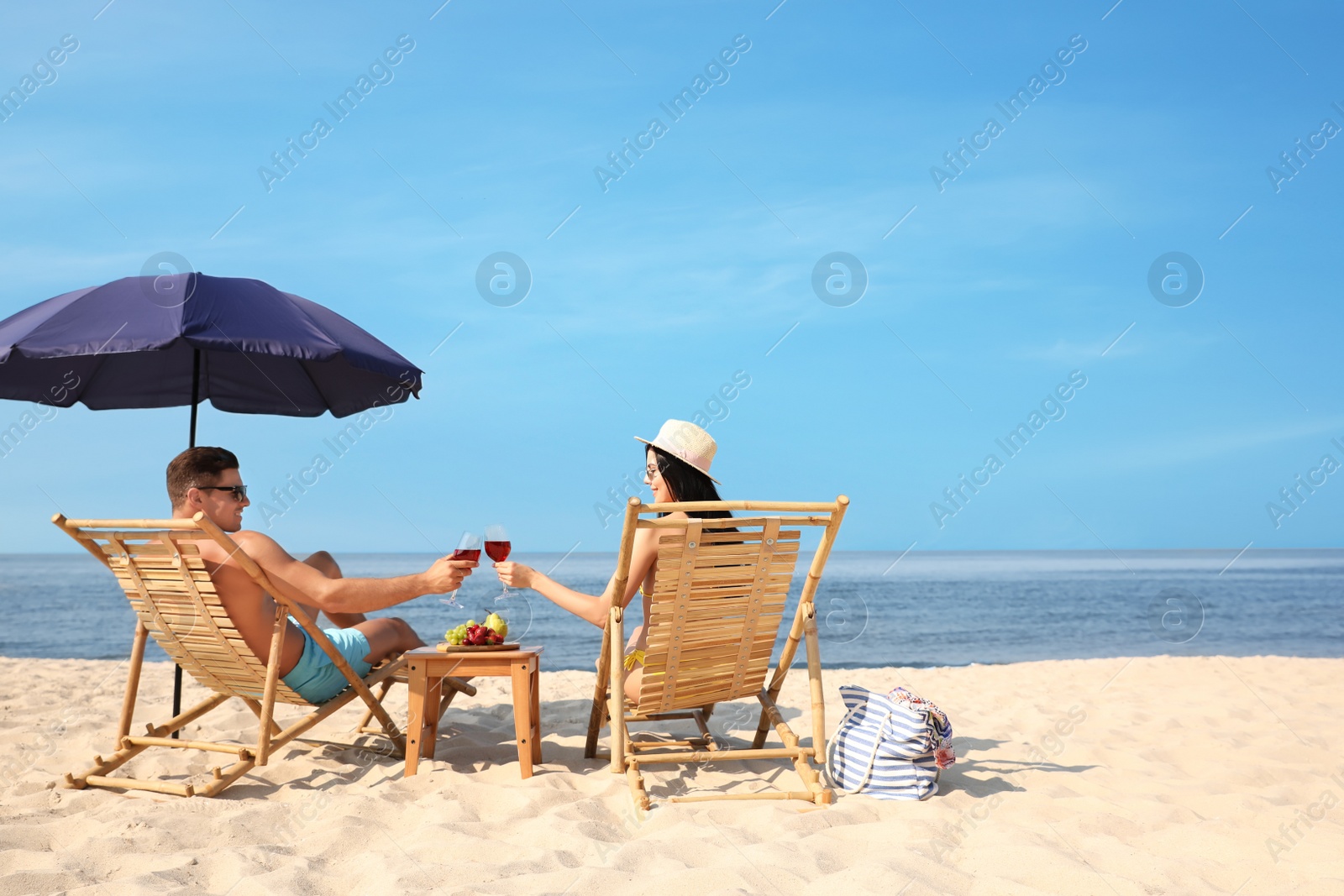 Photo of Happy couple with wine on sunny beach at resort