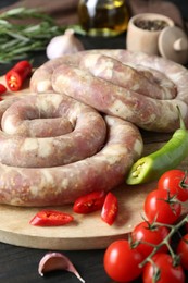 Raw homemade sausages, spices and other products on dark wooden table, closeup