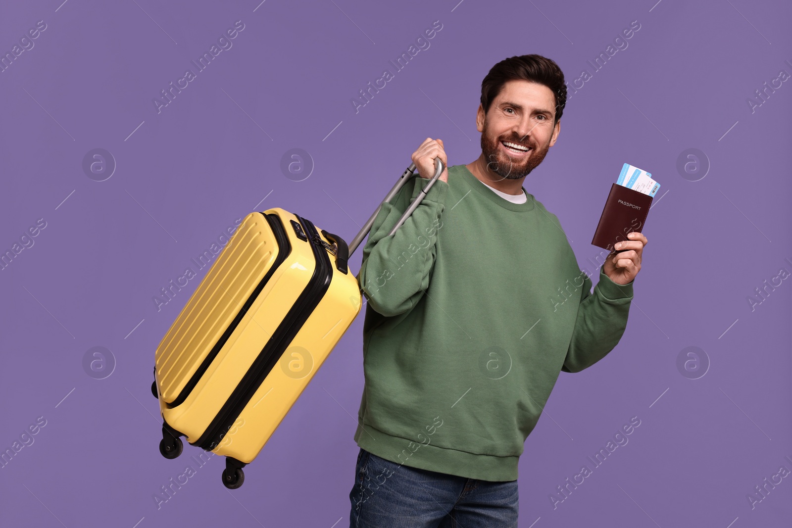 Photo of Smiling man with passport, tickets and suitcase on purple background