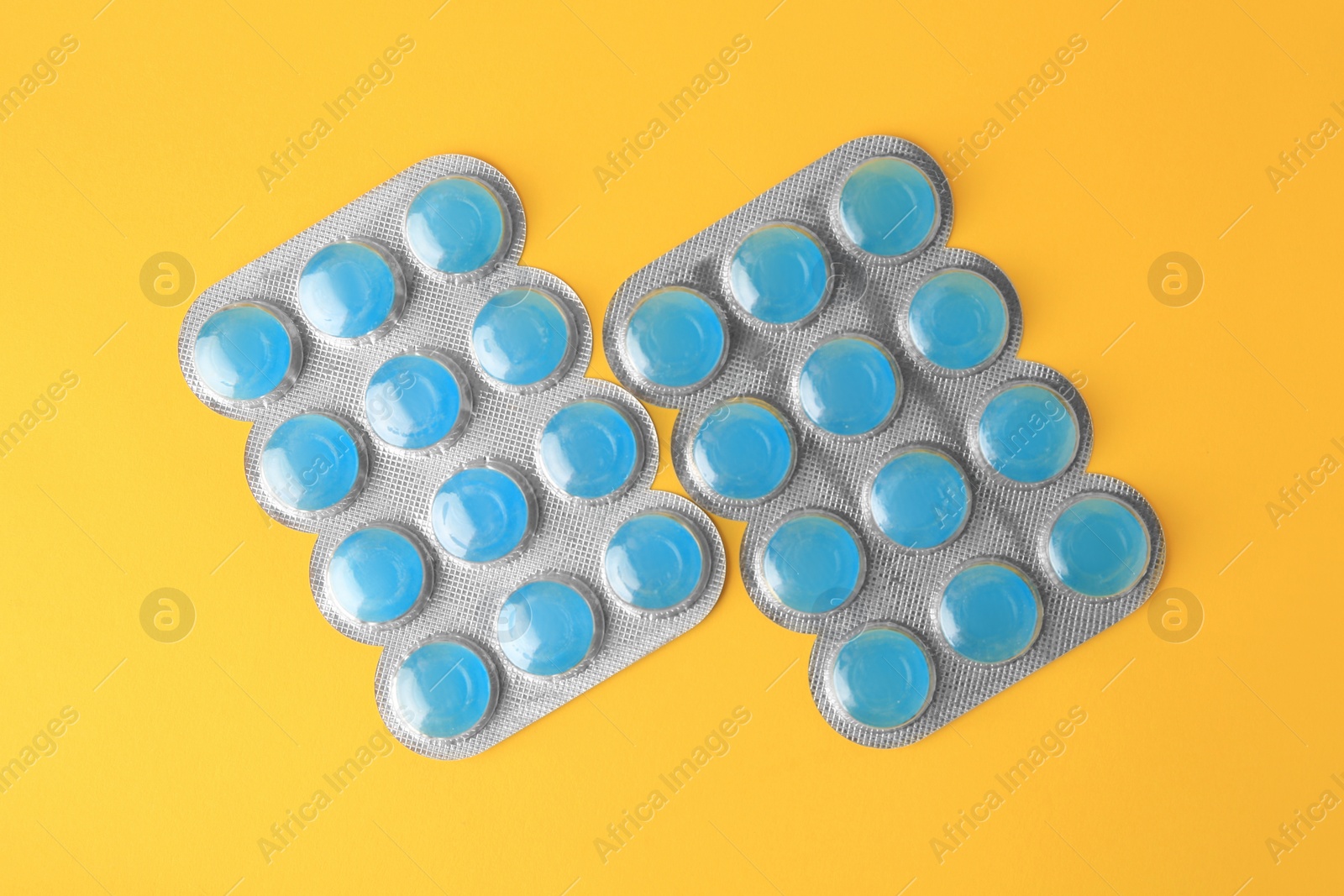 Photo of Blisters with cough drops on yellow background, flat lay