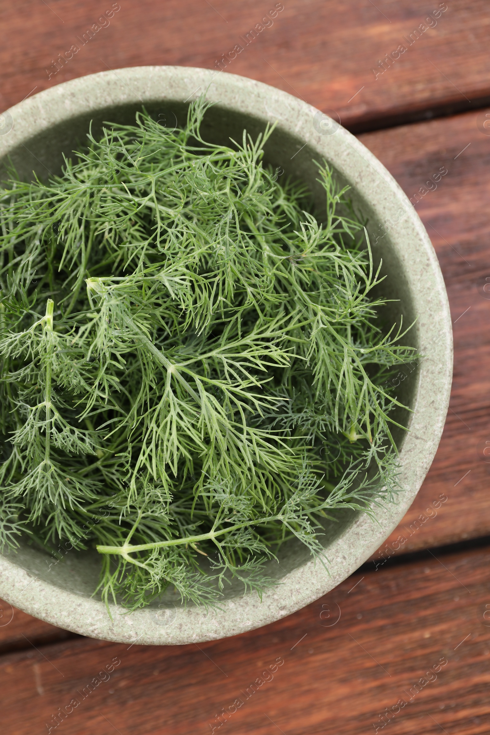 Photo of Bowl of fresh dill on wooden table, top view