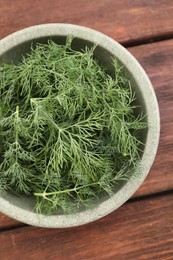 Photo of Bowl of fresh dill on wooden table, top view