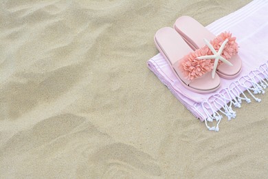 Photo of Blanket, stylish slippers and starfish on sand outdoors, above view with space for text. Beach accessories