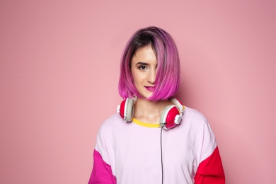 Photo of Young woman with trendy hairstyle and headphones against color background