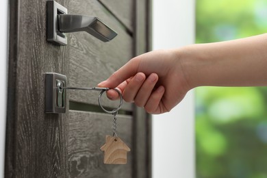 Photo of Woman unlocking door with key outdoors, closeup