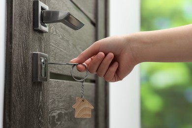 Woman unlocking door with key outdoors, closeup