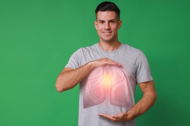 Handsome man holding hands near chest with illustration of lungs on green background